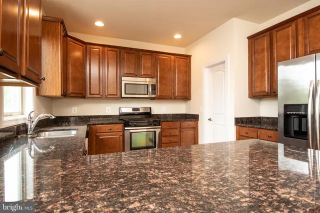 a kitchen with granite countertop cabinets stainless steel appliances a sink and wooden floor