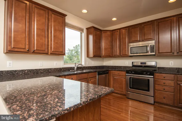 a kitchen with granite countertop wooden cabinets sink and window