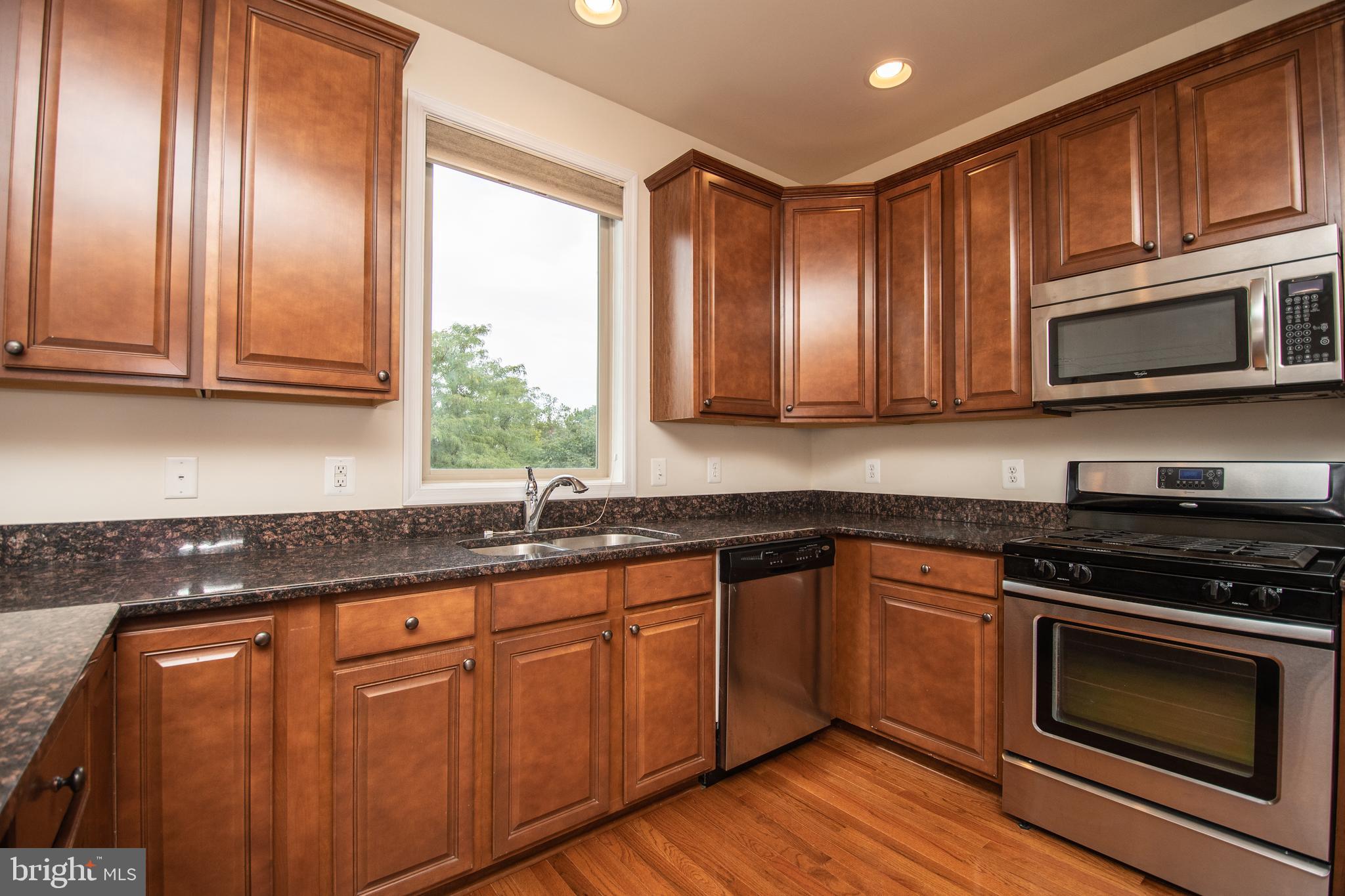 22199 Falling Terrace Ashburn, VA 20148 - Photo 26 of 58 a kitchen with granite countertop cabinets stainless steel appliances a sink and wooden floor