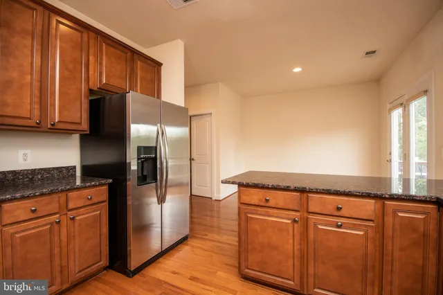 a kitchen with granite countertop a refrigerator and a stove top oven