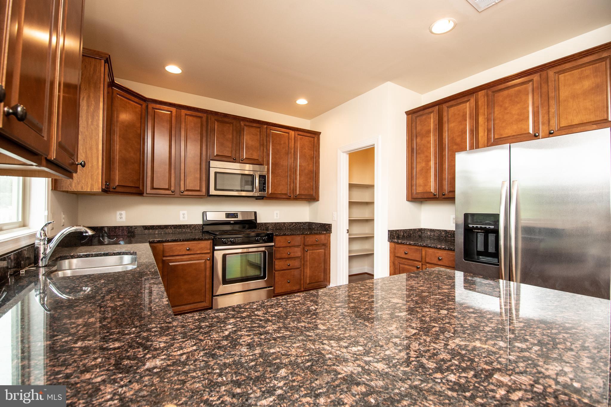 22199 Falling Terrace Ashburn, VA 20148 - Photo 30 of 58 a kitchen with granite countertop a refrigerator and a stove top oven