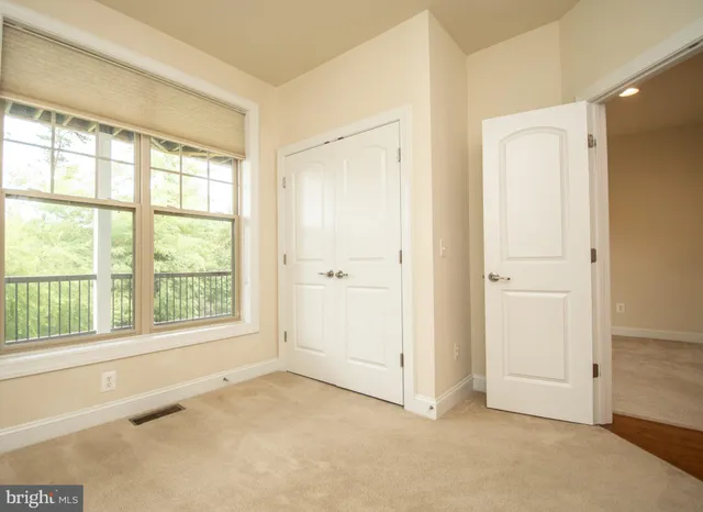 a view of an empty room with wooden floor and a bathroom