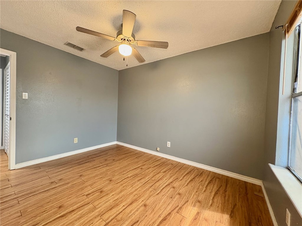 6702 Everhart Road, Unit H105 Corpus Christi, TX 78413 - Photo 11 of 18 wooden floor in an empty room with a window