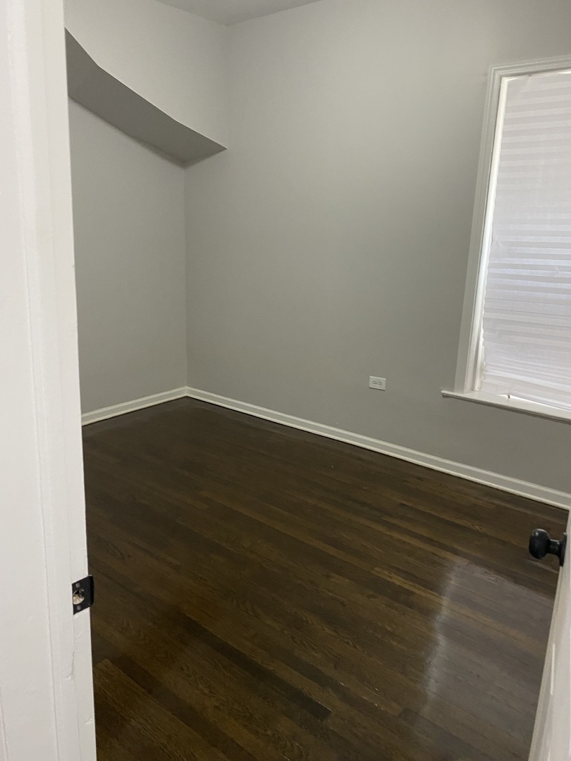 7425 South Princeton Avenue, Unit 2 Chicago, IL 60621 - Photo 5 of 24 an empty room with wooden floor and windows