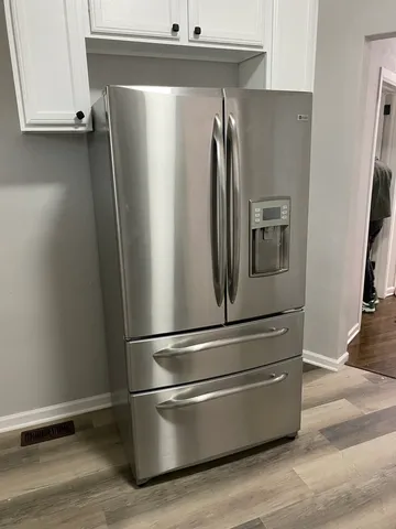 a view of a refrigerator in kitchen and an empty room