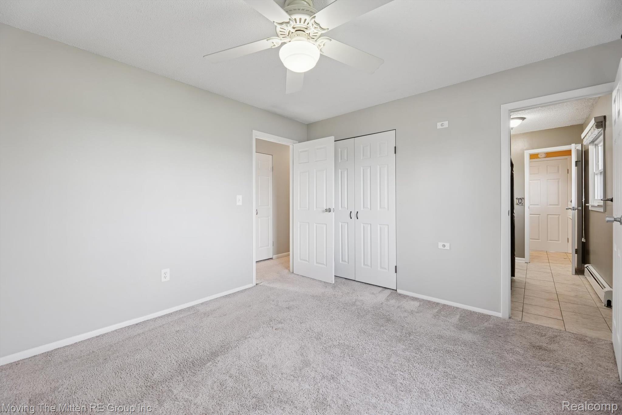 12000 Plank Road Milan, MI 48160 - Photo 20 of 49 Unfurnished bedroom featuring light colored carpet, a baseboard heating unit, ceiling fan, and a closet