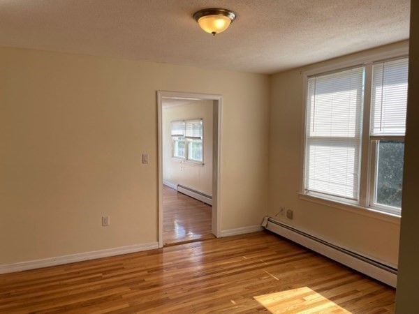 272-2 Nevada Street, Unit 2 Newton, MA 02460 - Photo 9 of 28 an empty room with wooden floor and windows