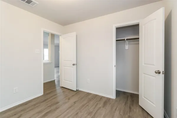 an empty room with wooden floor & closet area