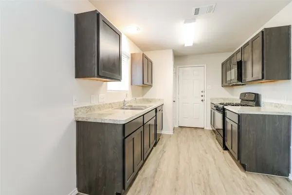 a kitchen with stainless steel appliances granite countertop a sink and a stove top oven