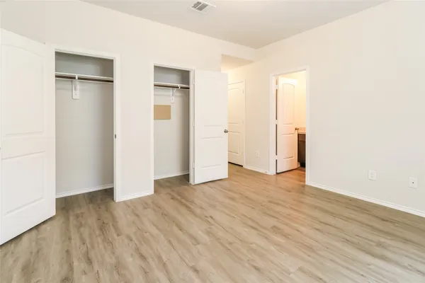 a view of an empty room with wooden floor and closet