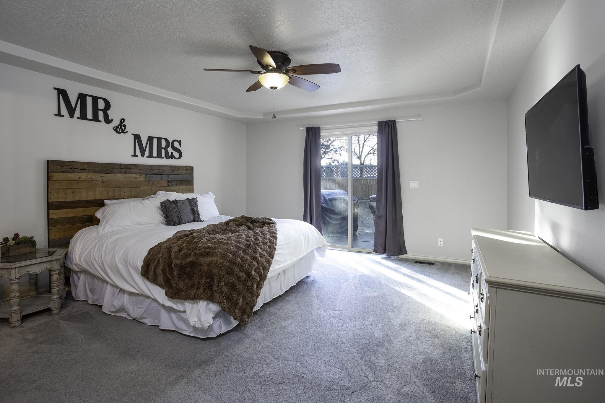 2217 East Satterfield Street Meridian, ID 83646 - Photo 11 of 33 Carpeted bedroom with access to outside, a ceiling fan, a textured ceiling, and a raised ceiling