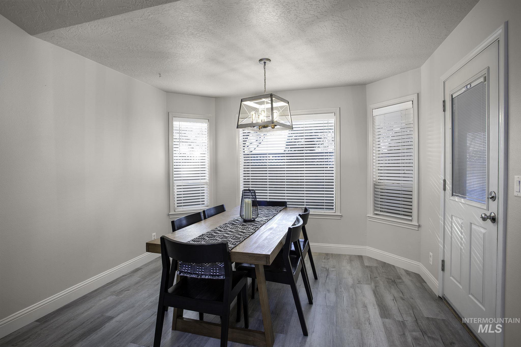 2217 East Satterfield Street Meridian, ID 83646 - Photo 7 of 33 Dining space with dark wood finished floors, plenty of natural light, a textured ceiling, and a chandelier