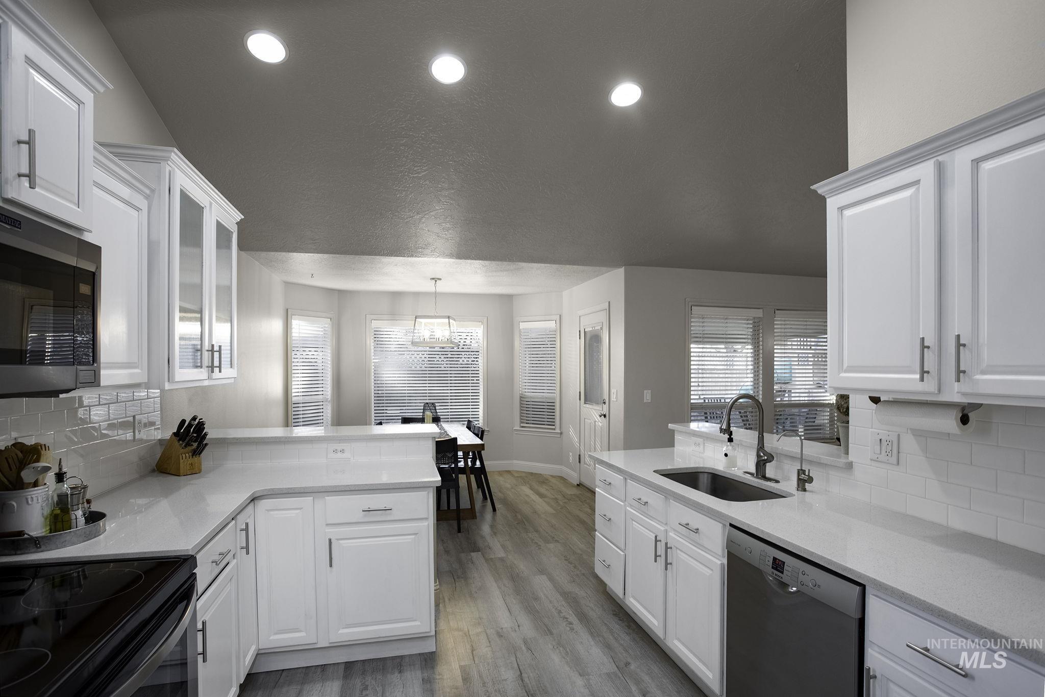 2217 East Satterfield Street Meridian, ID 83646 - Photo 9 of 33 Kitchen featuring a peninsula, decorative backsplash, light stone counters, stainless steel appliances, and recessed lighting
