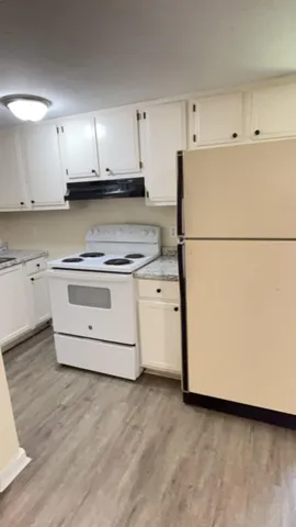 a kitchen with a stove a refrigerator and white cabinets