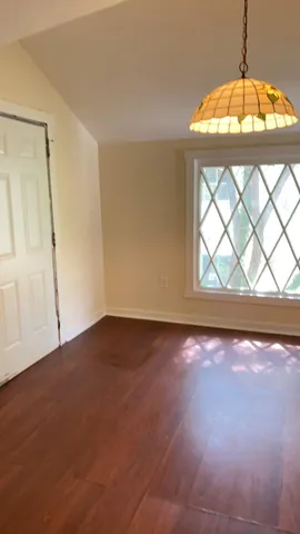 an empty room with wooden floor fan and window
