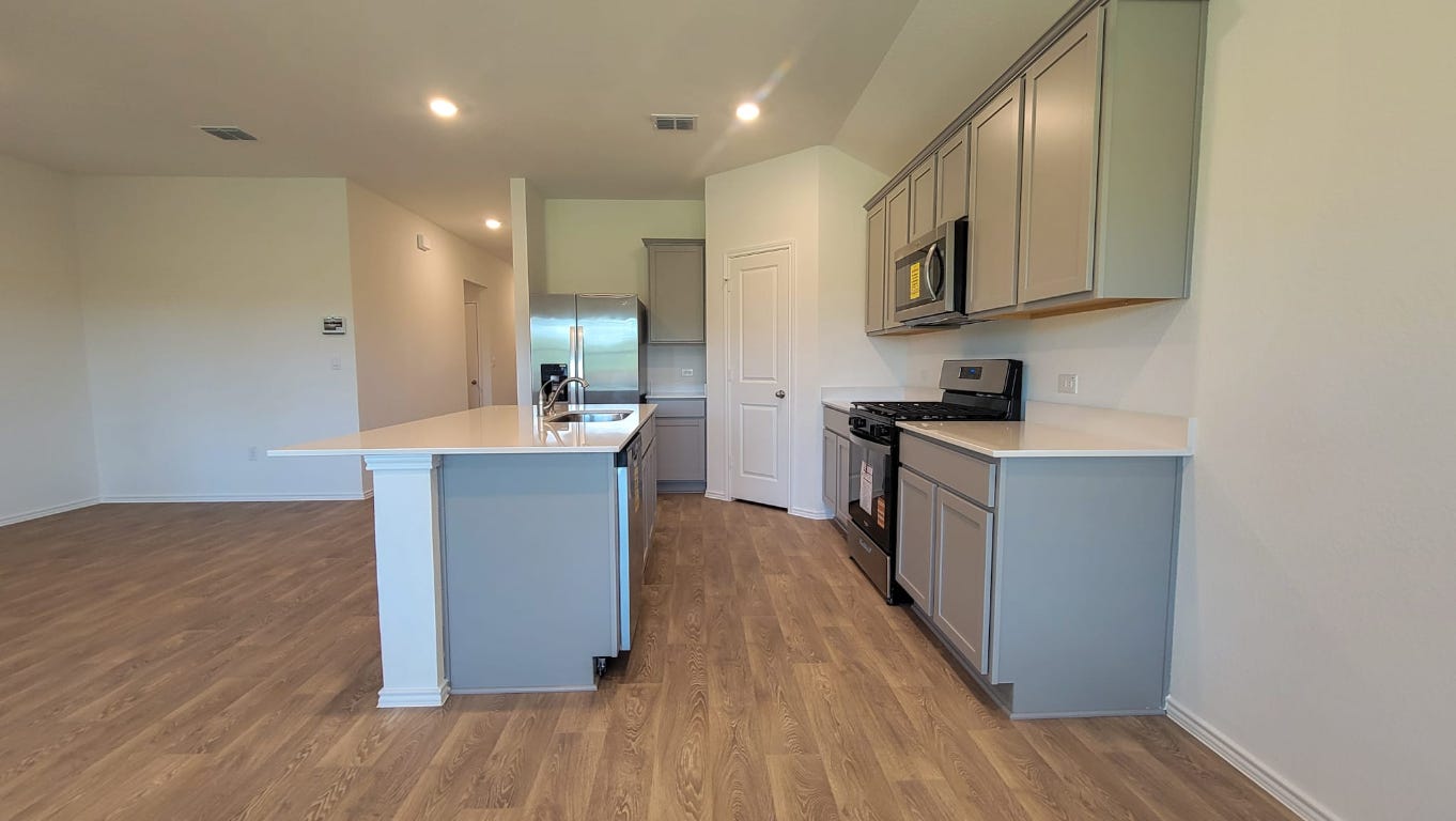 245 Texoma Street Kyle, TX 78640 - Photo 3 of 17 a kitchen with stainless steel appliances granite countertop a sink a stove a refrigerator cabinets and wooden floor