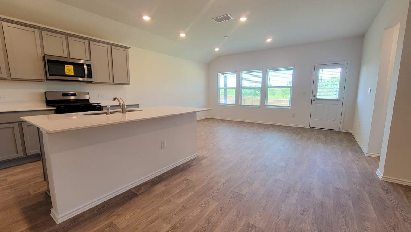 245 Texoma Street Kyle, TX 78640 - Photo 4 of 17 a kitchen with microwave a stove and wooden floor