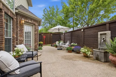 a view of a patio with plants and table and chairs under an umbrella