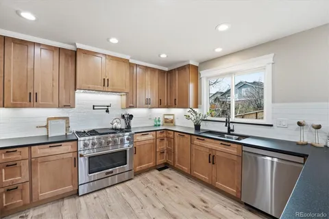 a kitchen with granite countertop cabinets stainless steel appliances a sink and a window