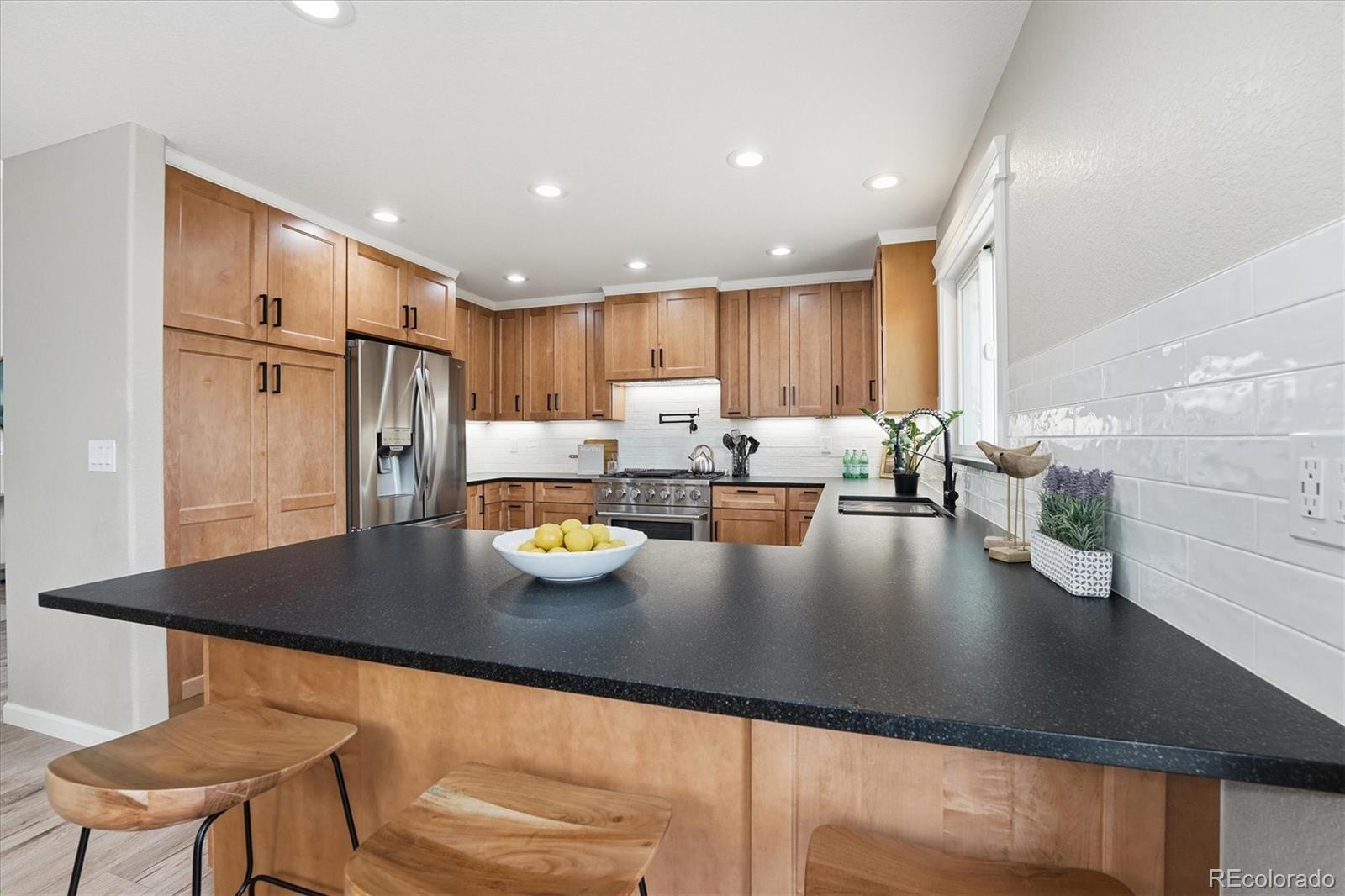 9387 Wolfe Drive Highlands Ranch, CO 80129 - Photo 14 of 50 a kitchen with stainless steel appliances granite countertop a sink refrigerator and cabinets