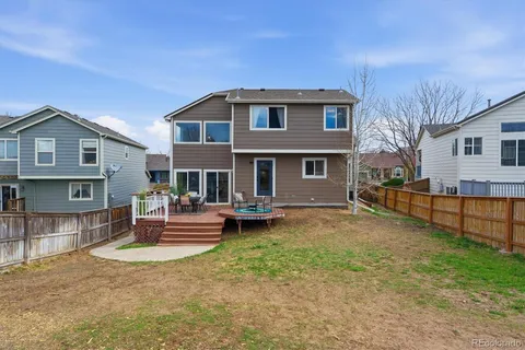 a view of a patio with couches table and chairs with wooden floor and fence
