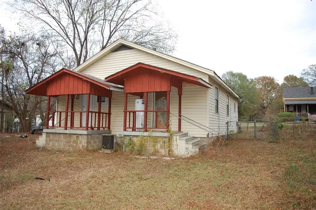 a backyard of a house with table and chairs under an umbrella