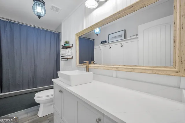 a bathroom with a granite countertop sink a toilet and a mirror