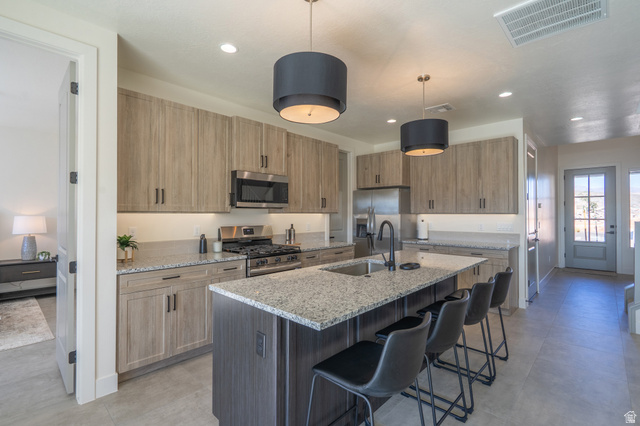 2972 West 570 North Hurricane, UT 84737 - Photo 35 of 104 Kitchen with light stone countertops, stainless steel appliances, a kitchen breakfast bar, a center island with sink, and hanging light fixtures