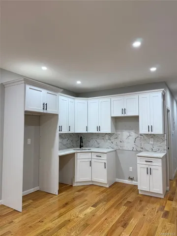 a kitchen with a stove a refrigerator and white cabinets