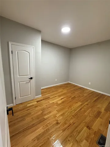 an empty room with wooden floor and mirror