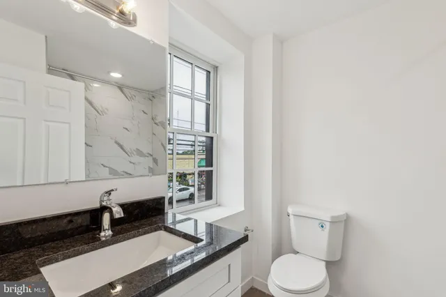a bathroom with a granite countertop sink a toilet and bathtub