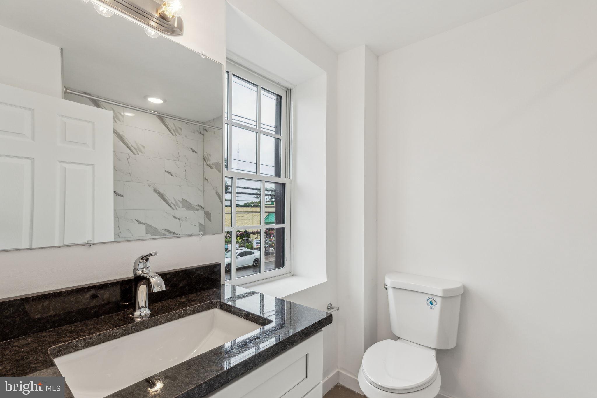 7039 Ridge Avenue Philadelphia, PA 19128 - Photo 22 of 26 a bathroom with a granite countertop sink a toilet and bathtub