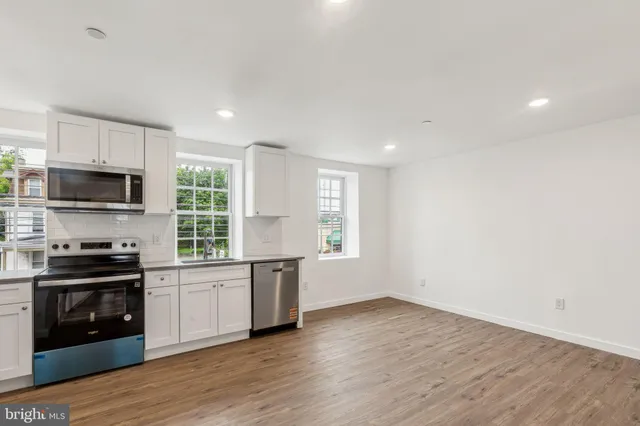 a kitchen with granite countertop a stove top oven a sink dishwasher a refrigerator and a microwave with wooden floor