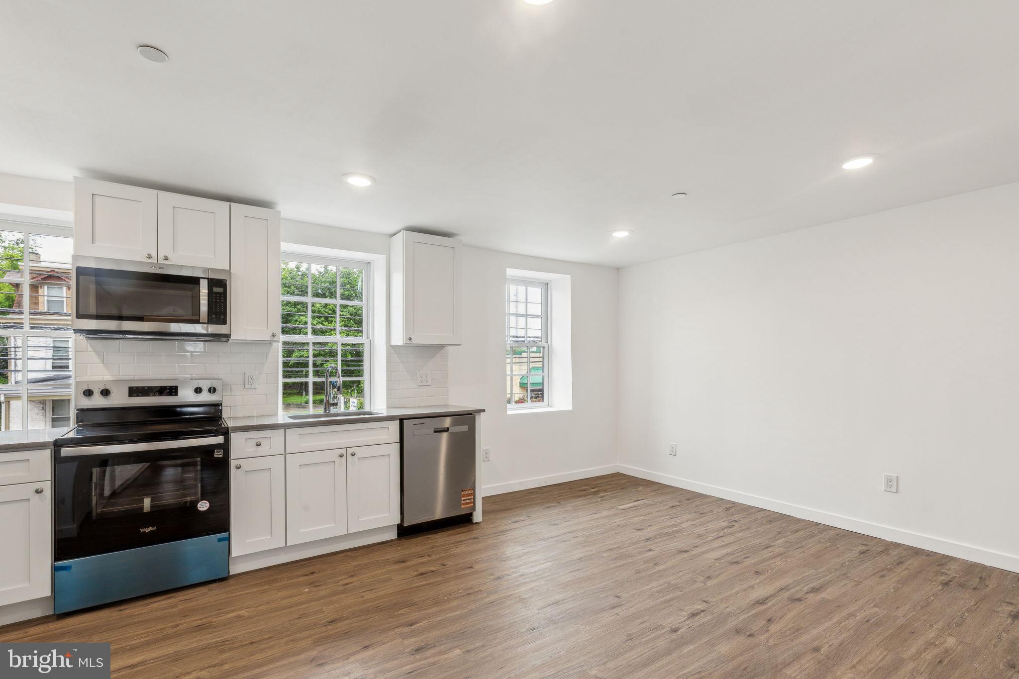 7039 Ridge Avenue Philadelphia, PA 19128 - Photo 4 of 26 a kitchen with granite countertop a stove top oven a sink dishwasher a refrigerator and a microwave with wooden floor