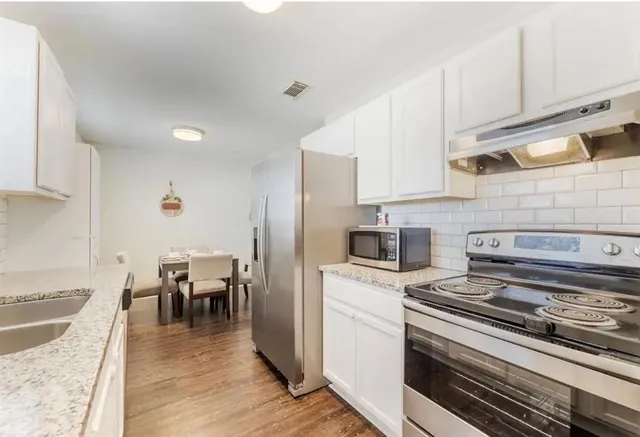 a kitchen with a stove cabinets and wooden floor