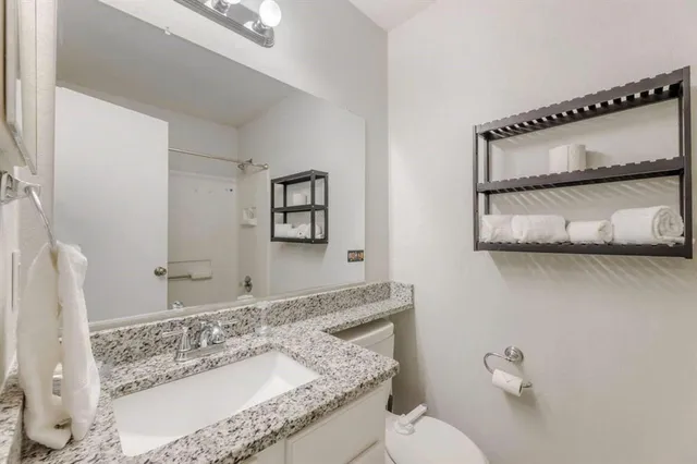 a bathroom with a granite countertop sink mirror and toilet