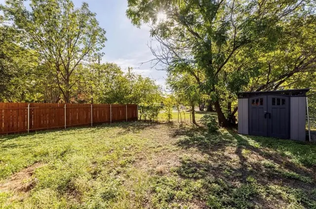 a view of a backyard with wooden fence and a large tree