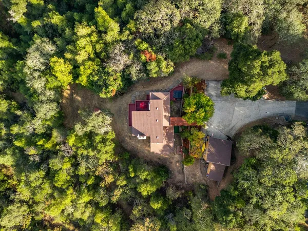 an aerial view of residential house with outdoor space and trees all around