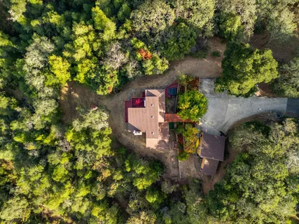 an aerial view of residential house with outdoor space and trees all around