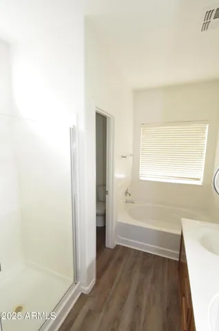 a view of an empty room with wooden floor and a bathroom