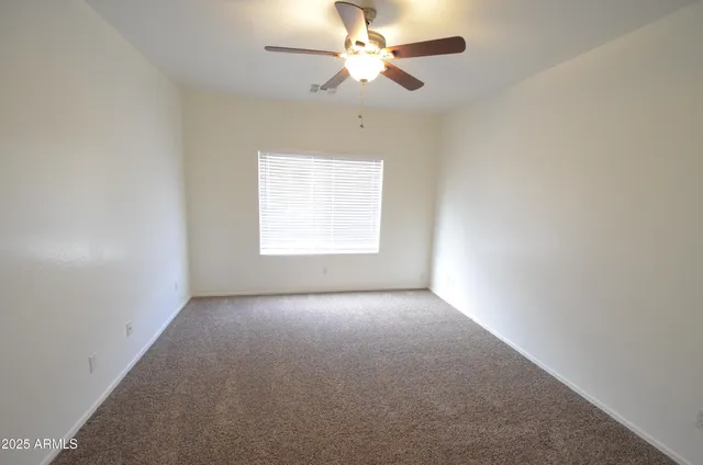 an empty room with a chandelier fan and windows