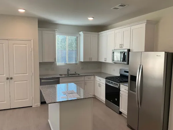 a kitchen with stainless steel appliances granite countertop a sink and a refrigerator