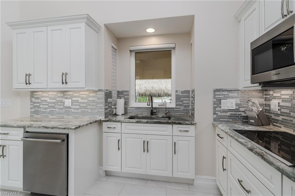 13410 Snook Circle Naples, FL 34114 - Photo 18 of 50 a kitchen with granite countertop white cabinets and stainless steel appliances
