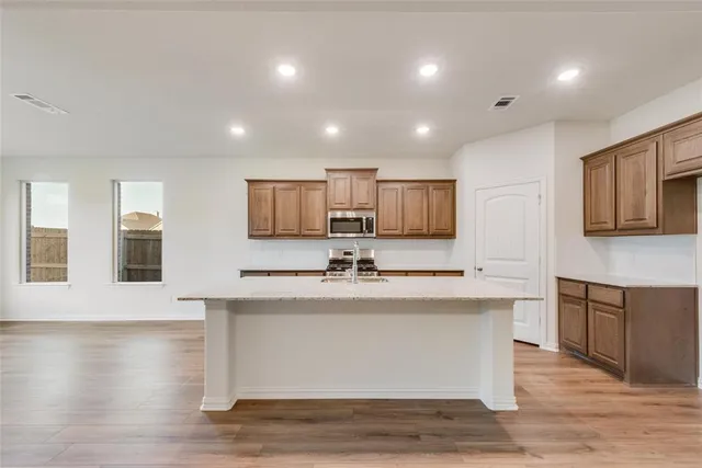 a large kitchen with stainless steel appliances wooden floor and a counter top space