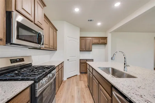 a kitchen with stainless steel appliances granite countertop a sink stove microwave and refrigerator
