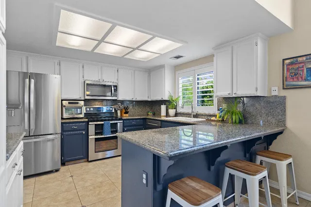 a kitchen with granite countertop a stove refrigerator and microwave