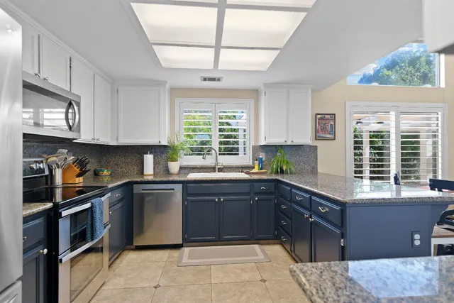 a kitchen with stainless steel appliances granite countertop wooden cabinets a sink and a stove