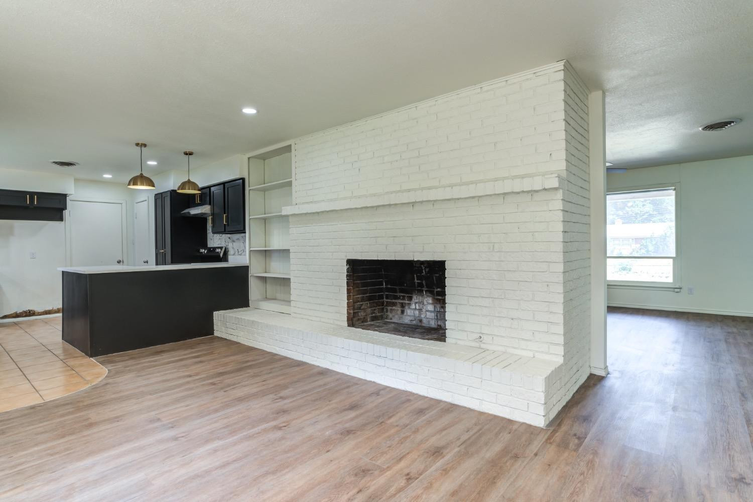 2119 67th Street Lubbock, TX 79412 - Photo 14 of 42 a living room with stainless steel appliances kitchen island a fireplace wooden floor and a fireplace