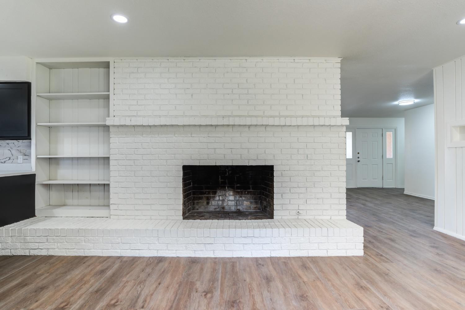 2119 67th Street Lubbock, TX 79412 - Photo 15 of 42 a living room with a fireplace and a wooden floor