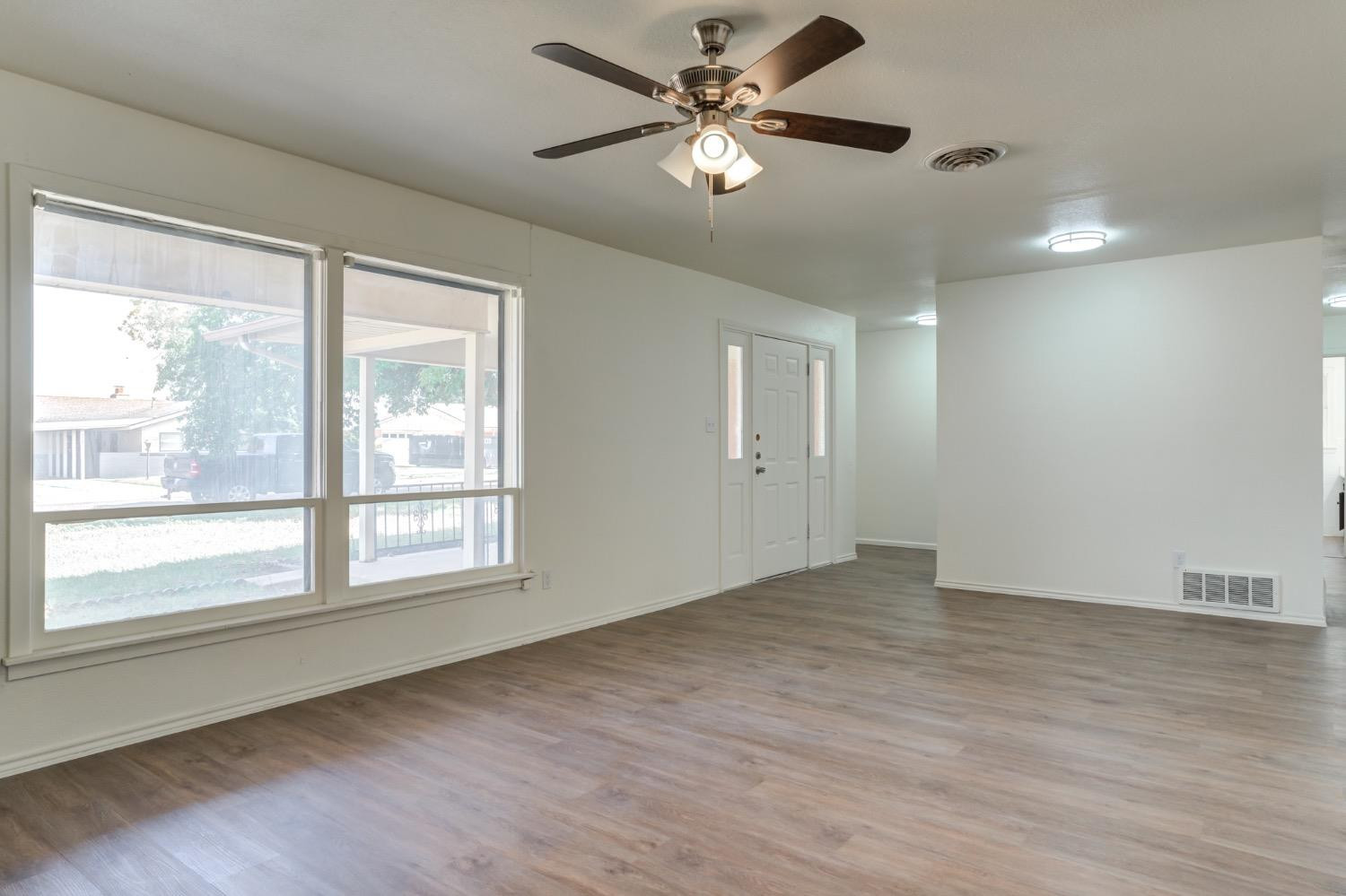 2119 67th Street Lubbock, TX 79412 - Photo 8 of 42 a view of an empty room with a window and wooden floor